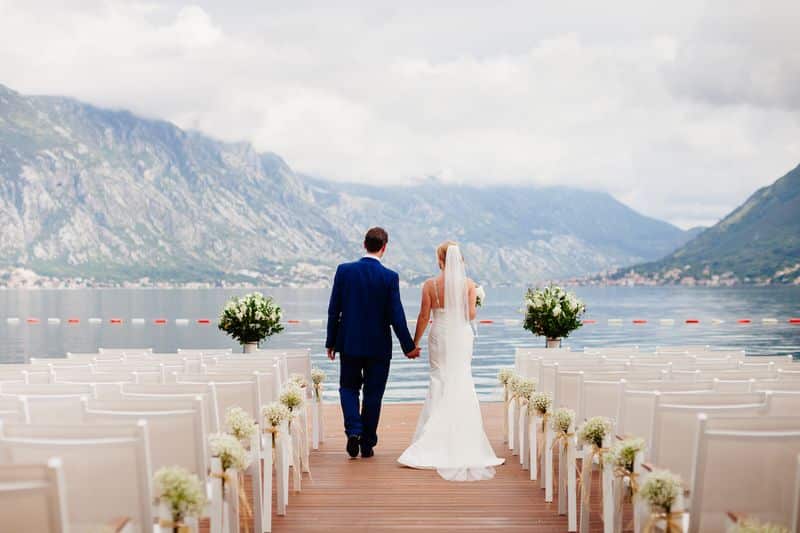 Husband and wife walking down the aisle that is on the lake